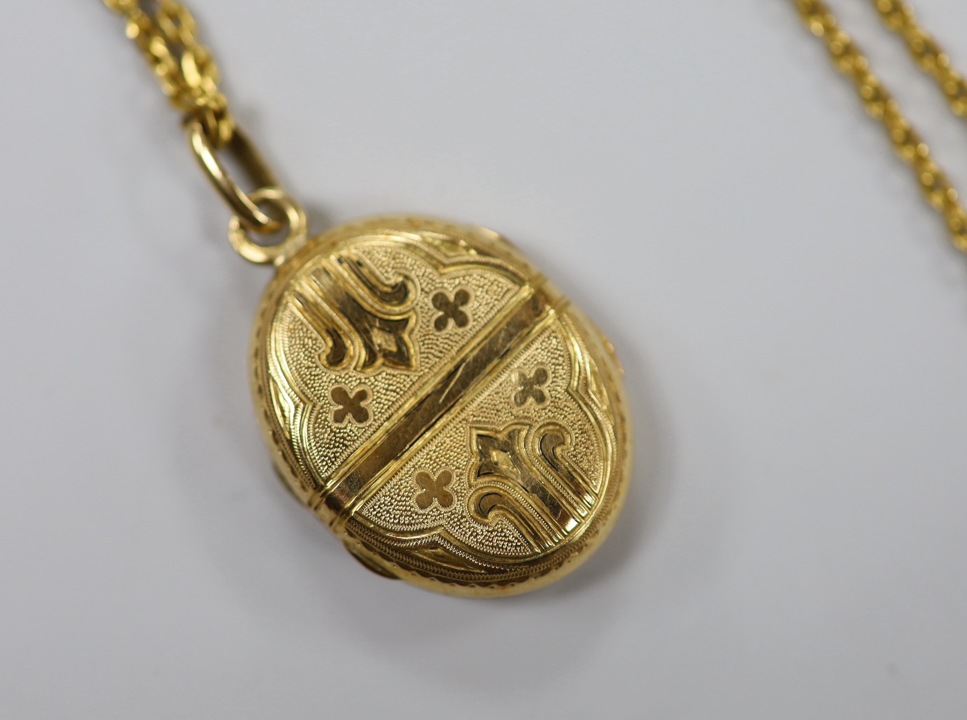 A continental engraved yellow metal oval locket, overall 38mm, on a 9ct chain, 47cm, gross weight 18.9 grams.